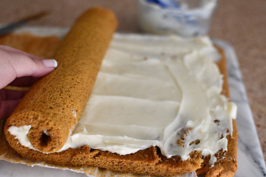 rolling up a cake with cream cheese frosting 