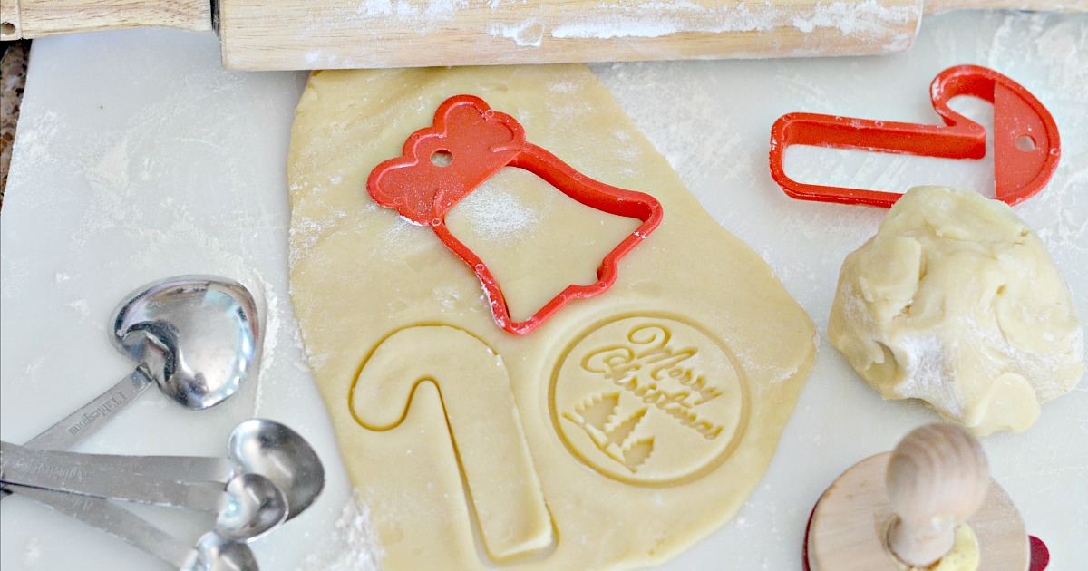 rolled raw cookie dough with christmas cutouts on table