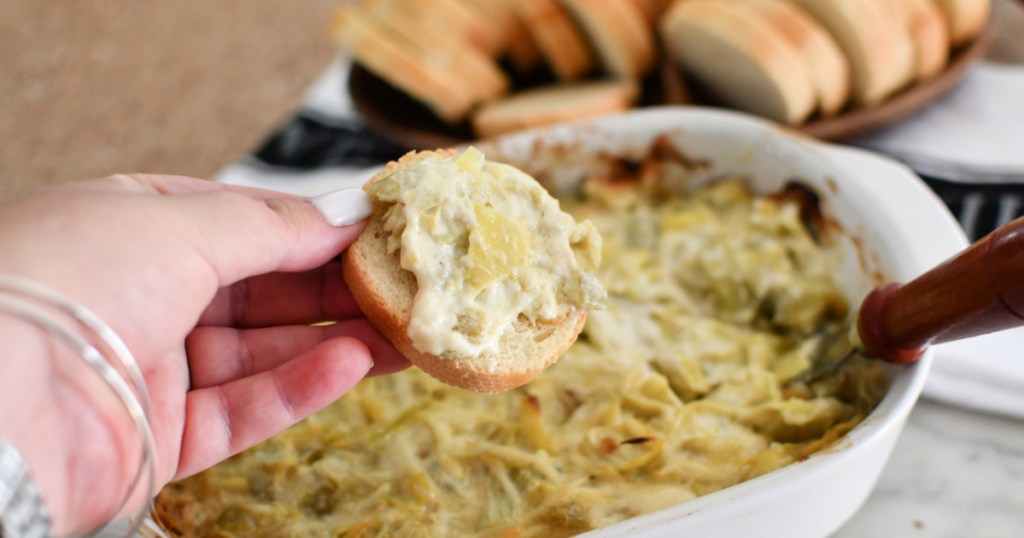 spreading artichoke dip on bread