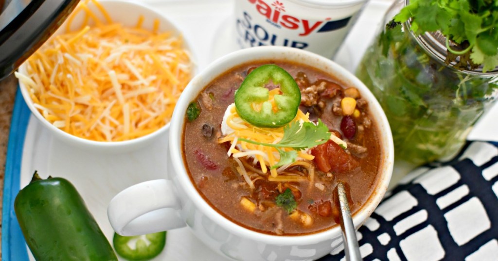 bowl of ranch taco soup next to cilantro and cheese