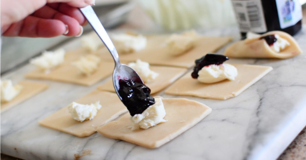 spooning blackberry jam onto pie crusts