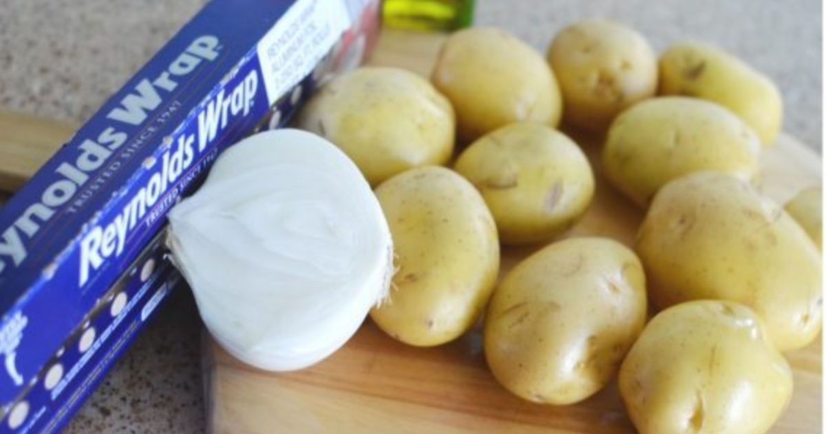 Reynolds wrap, potato, and onions on a cutting board