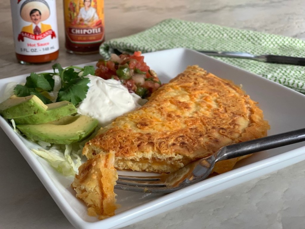 keto quesadilla on plate with avacado, sour cream, and salsa