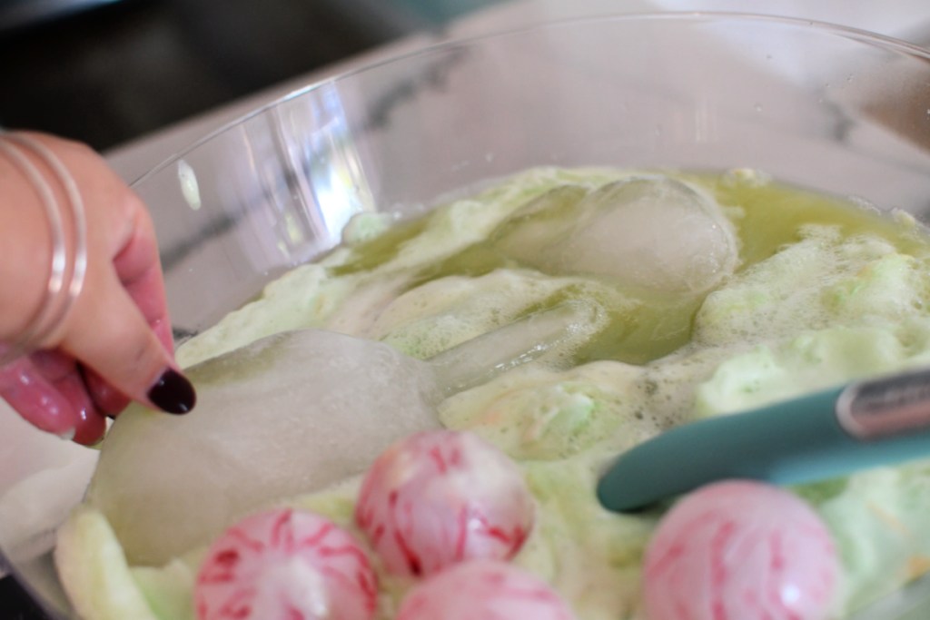 adding hand ice cubes to green halloween punch