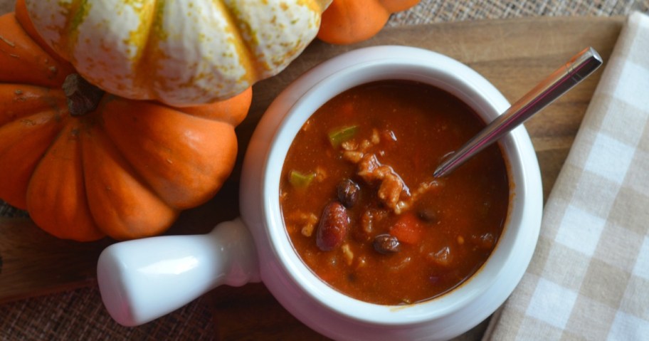 pumpkin chili in a bowl next to pumpkins