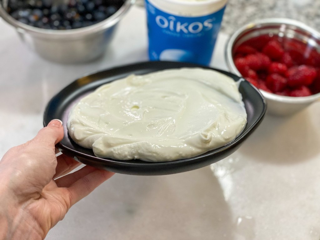 hand holding black plate with white yogurt on it