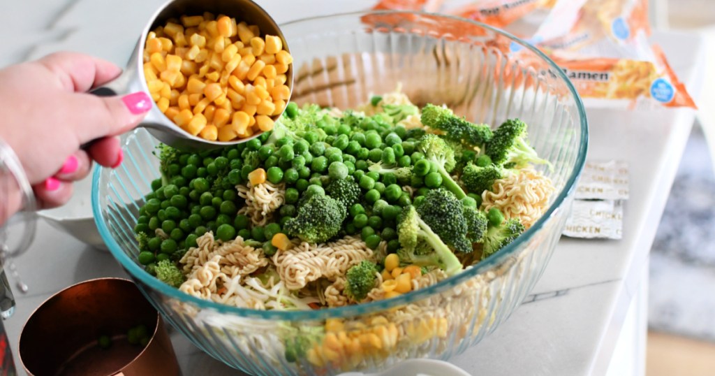 adding corn and veggies to ramen salad