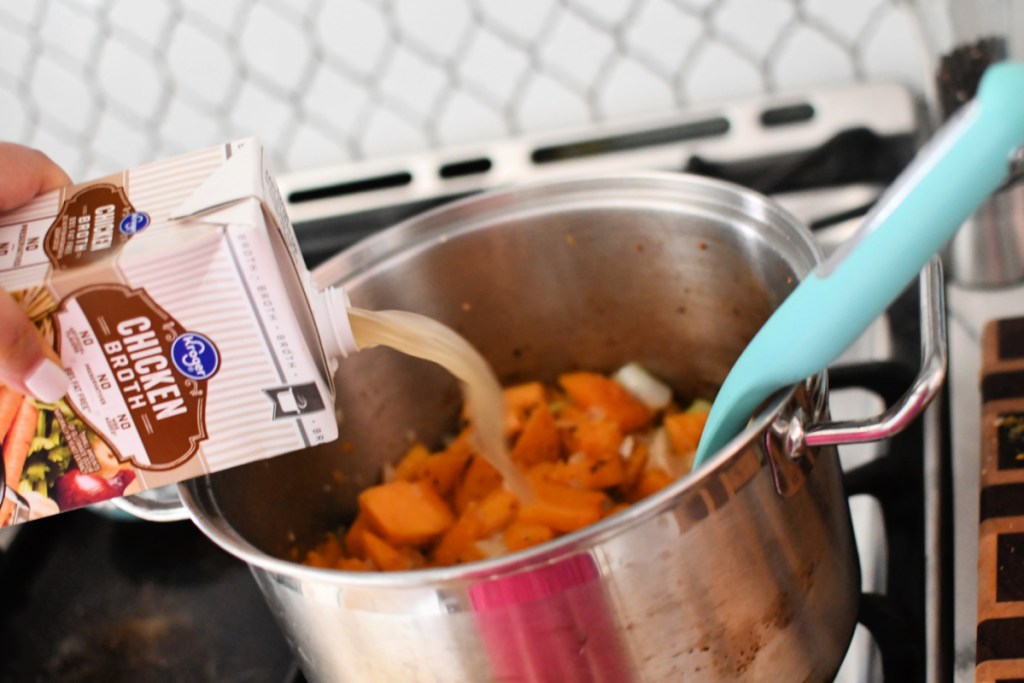 adding broth to a pot of veggies