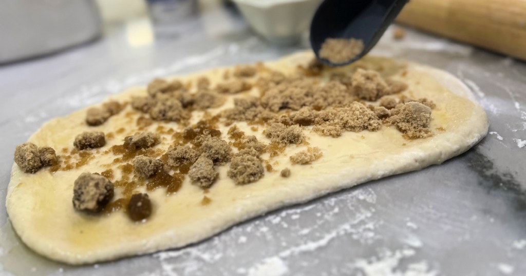 adding butter and brown sugar to dough for cinnamon rolls