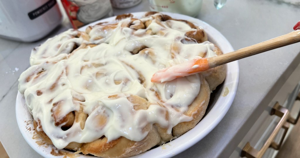 spreading cinnamon rolls with cream cheese glaze