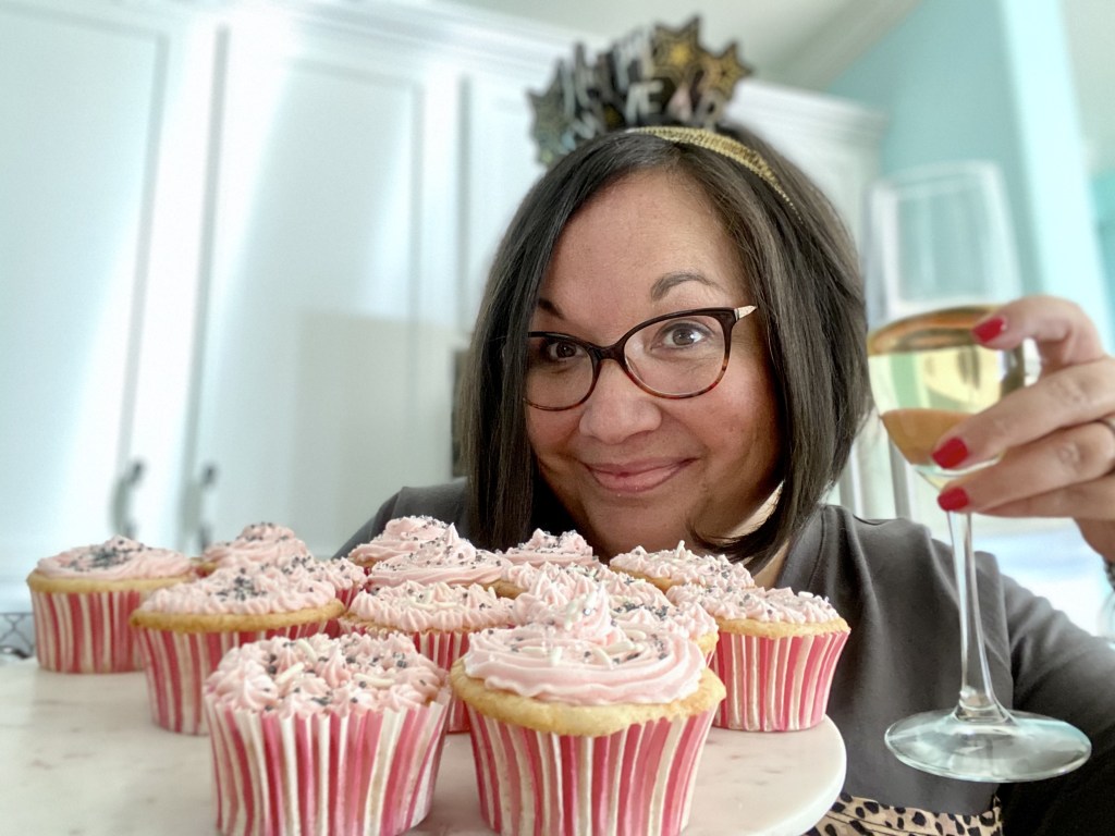 woman holding champagne and cupcakes