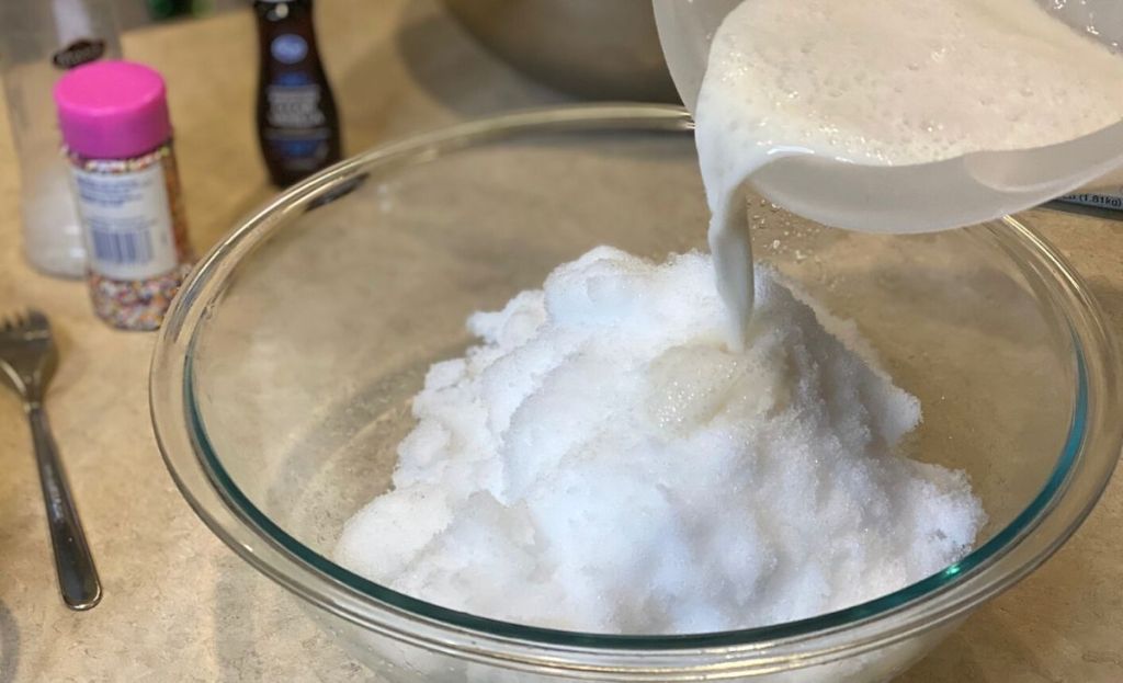 Pouring a milk mixture into some snow in a bowl