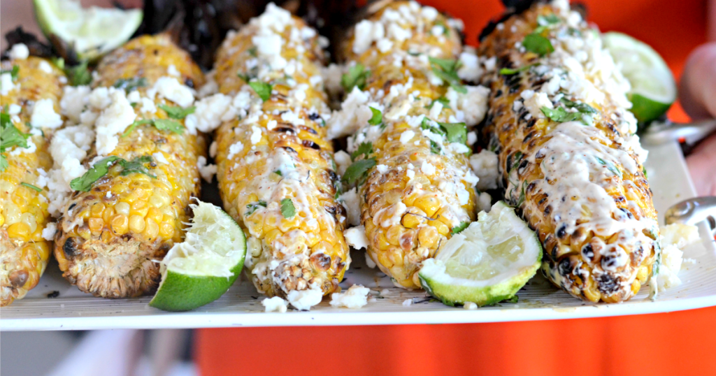 holding a tray of mexican grilled corn