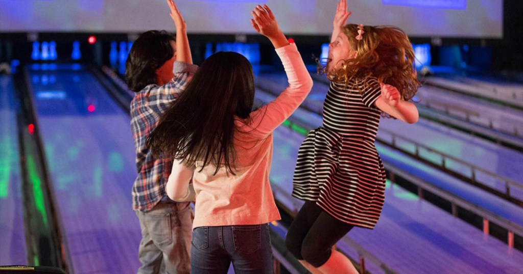 three kids high-fiving at bowling alley