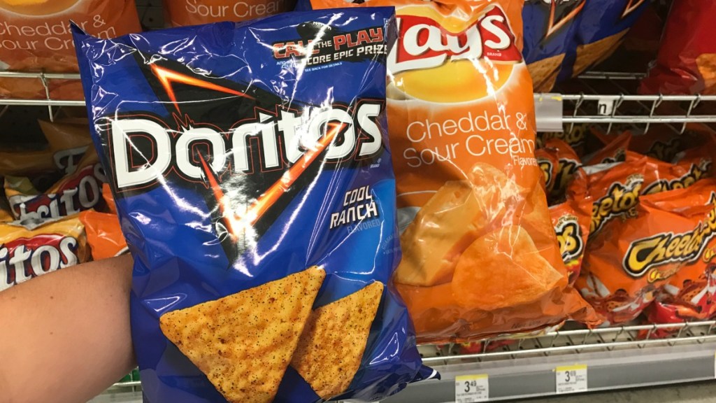 hand holding chips in front of shelf 