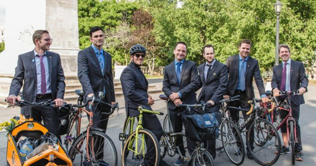 Men wearing suits on bikes