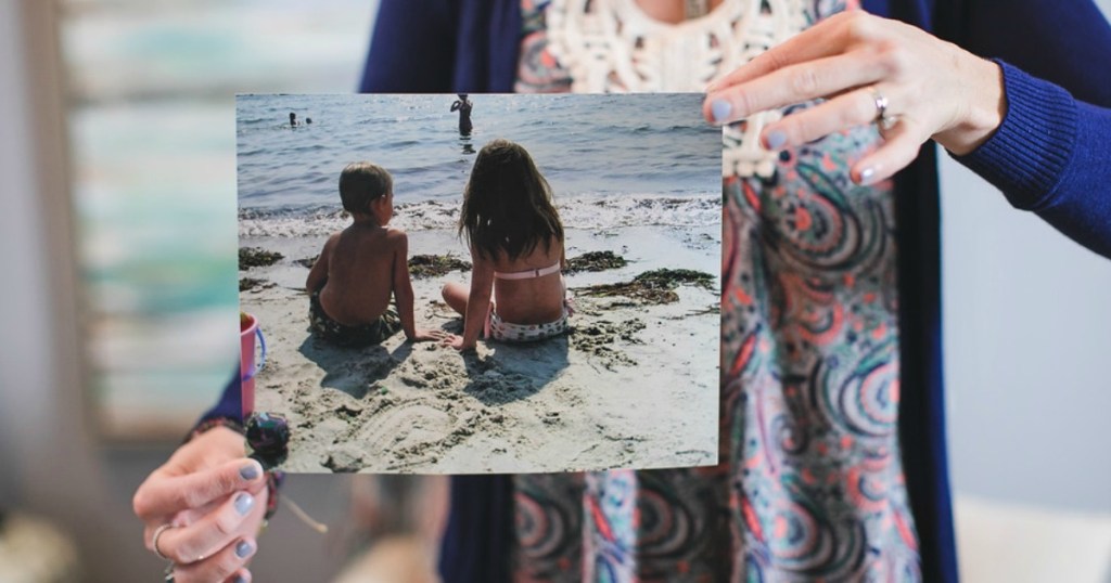 woman holding 8x10 photo print of kids at the beach