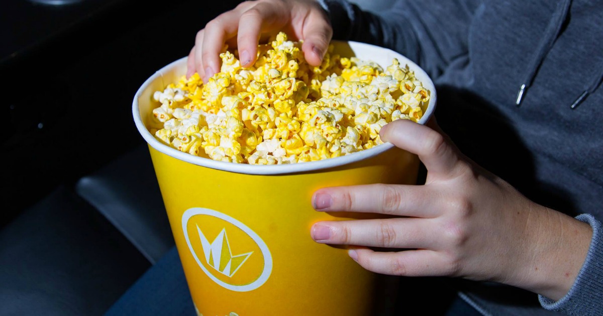 person eating from a Regal popcorn bucket at Regal cinemas