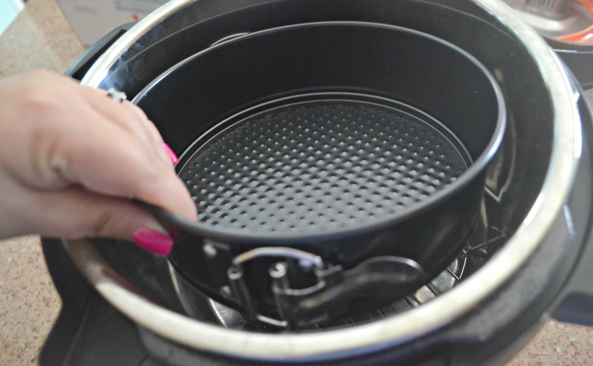 woman placing a cheesecake pan in a pressure cooker