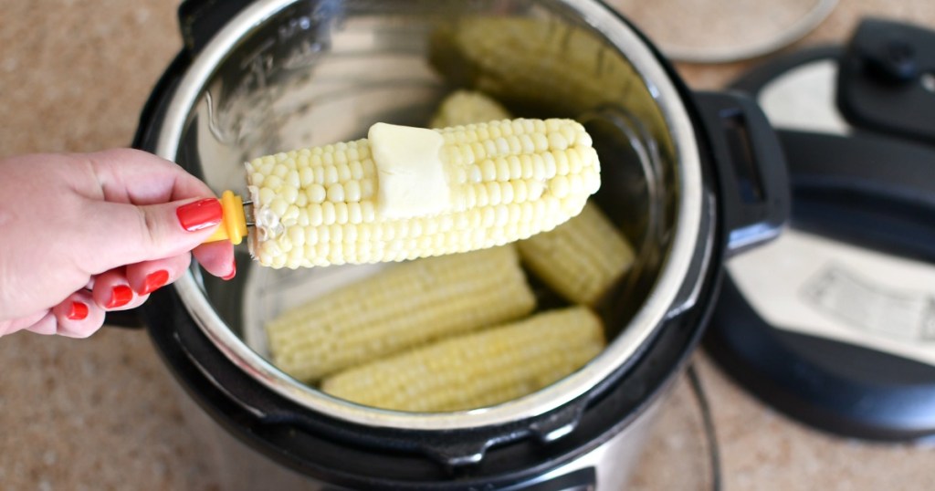 woman holding an ear of steamed corn