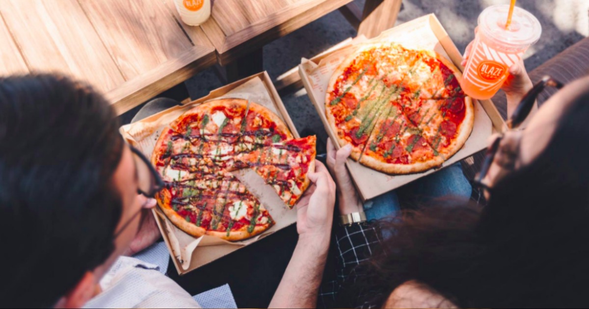 two people eating blaze pizzas in boxes