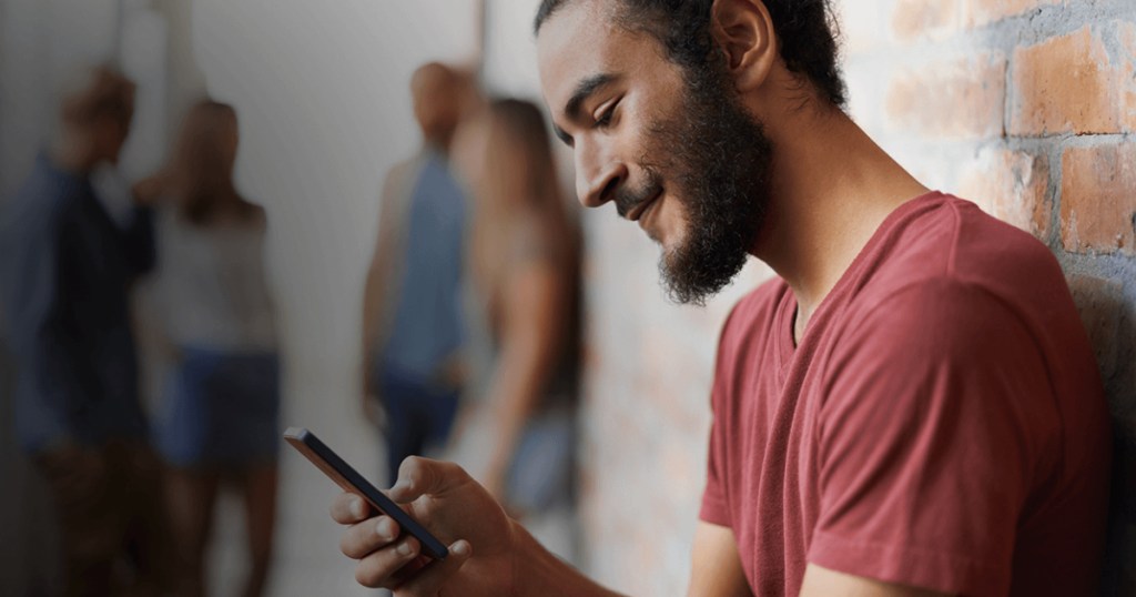 man holding cell phone smiling at screen