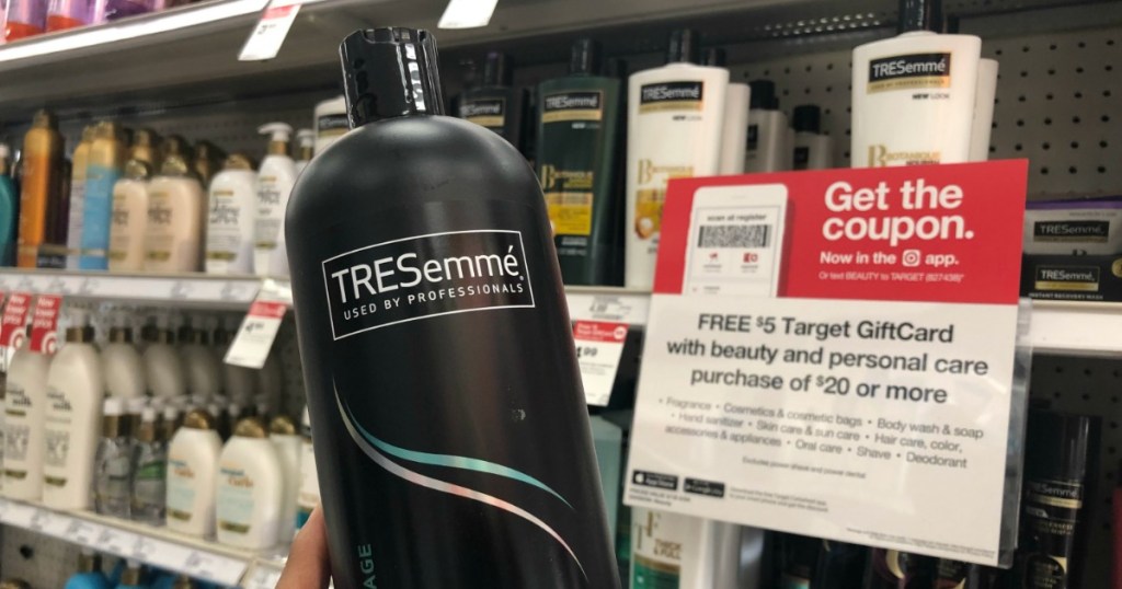 hand holding tresemme shampoo in front of gift card sign