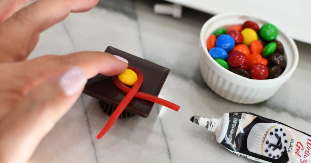 adding an m and m twizzlers to graduation hat