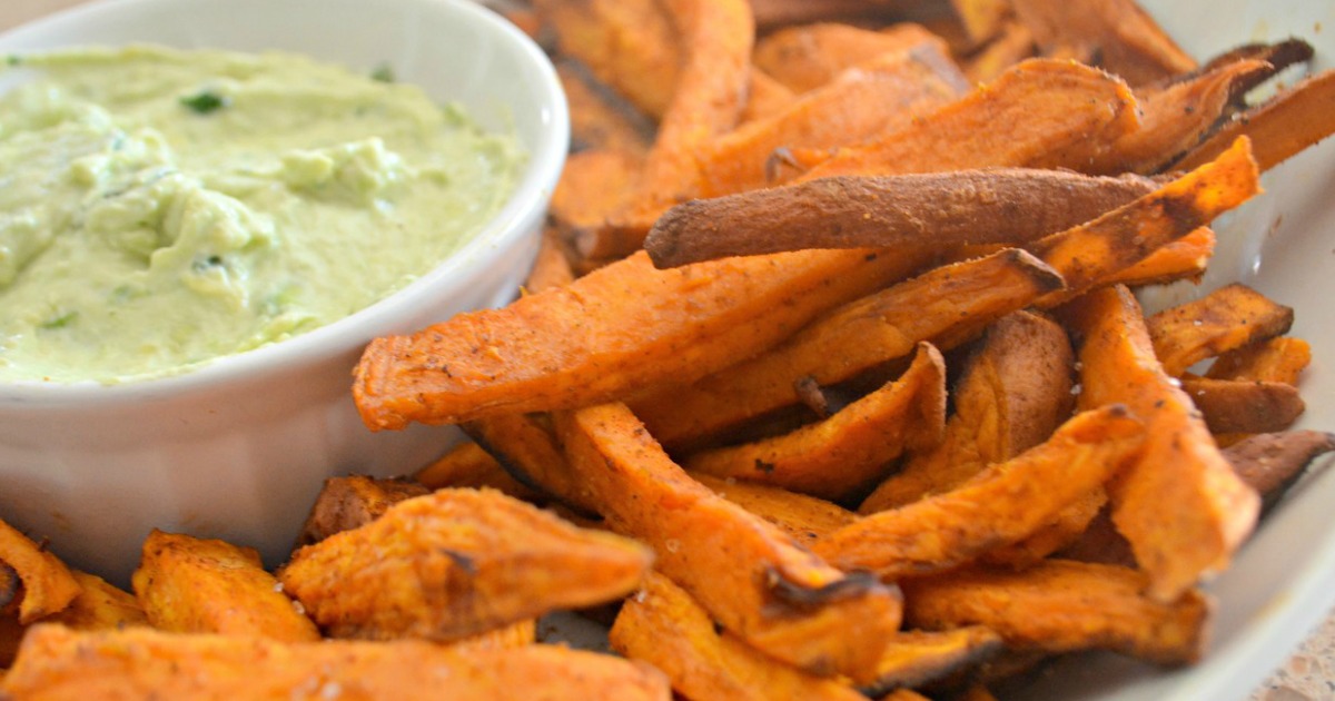 A plate with warm sweet potato fries and an avocado dipping sauce. 