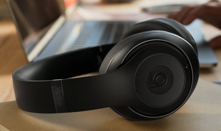 a pair of black Beats handphones on a desk next to a laptop