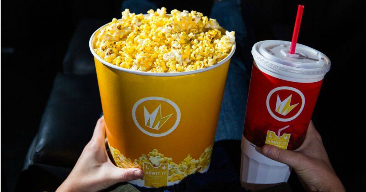 Person holding popcorn and soda at Regal movie theater