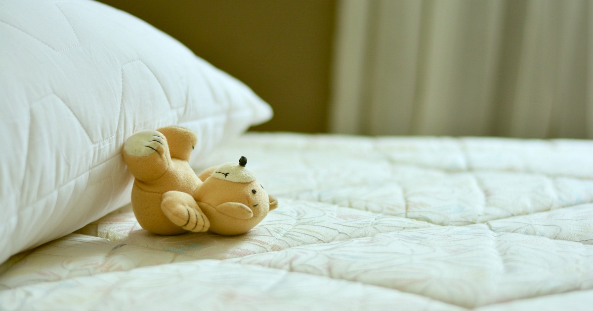 close up of mattress with stuffed teddy bear and pillow