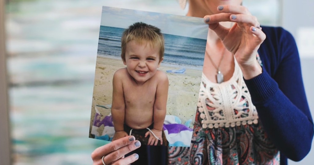 Holding 8x10 photo print of little boy 