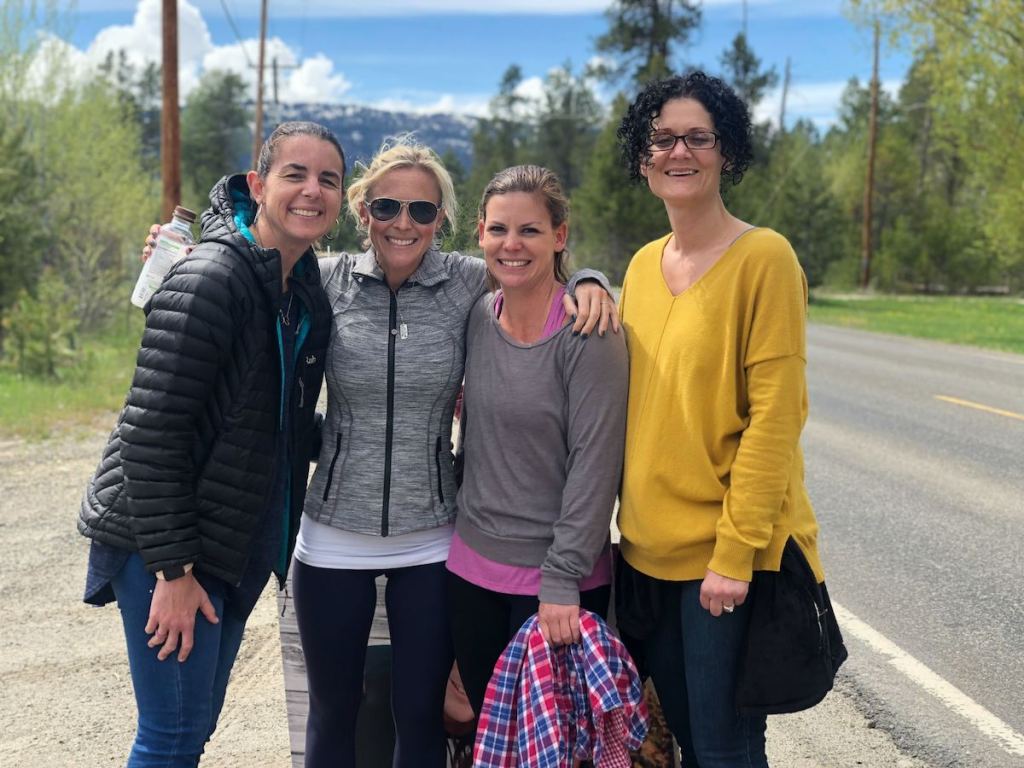 Four women standing on side of road outside