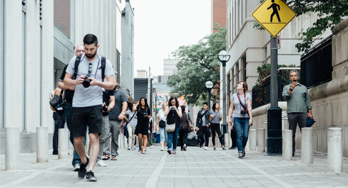 man checking his camera as he walks along the street