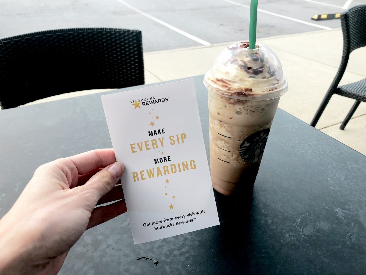 starbucks rewards flyer in hand near Starbucks Frappuccino