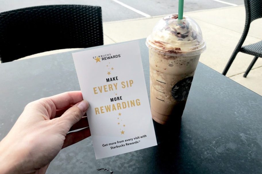 starbucks rewards in hand with drink on table