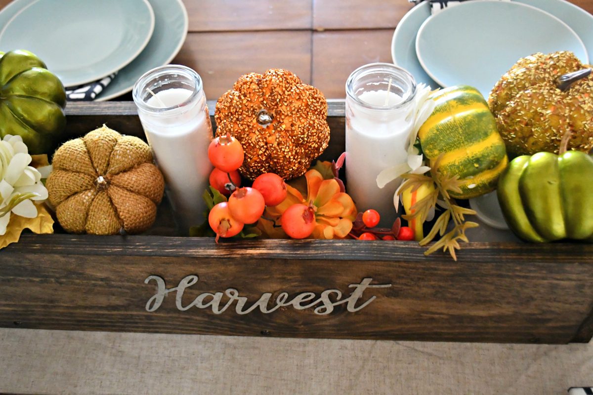 dollar tree fall centerpiece - this is a side view of the wooden box with pumpkins, greenery, and "harvest" lettering