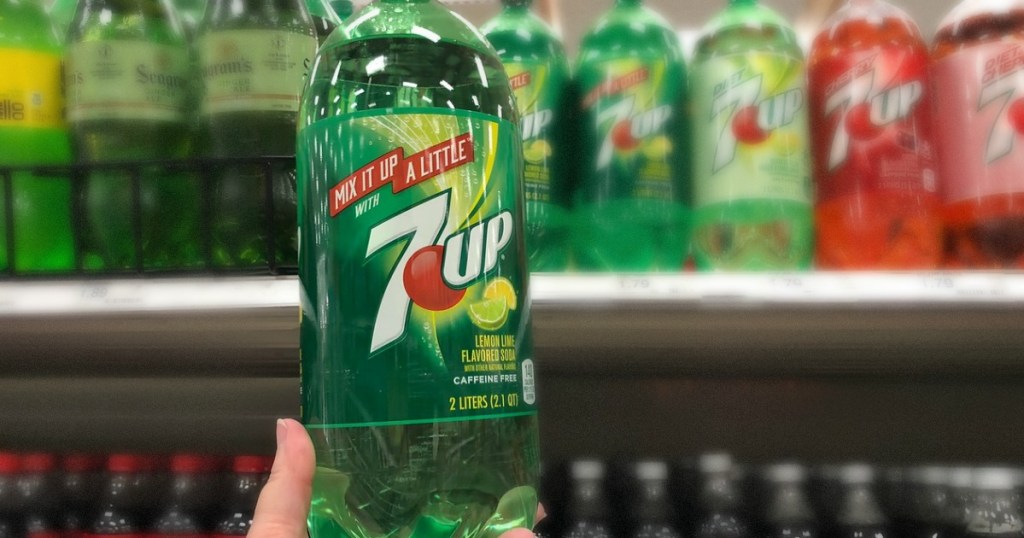 hand holding bottle of soda in front of shelf 