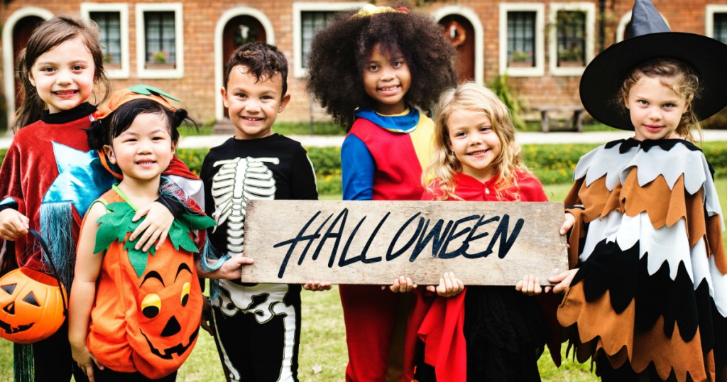 kids in costumes holding a Halloween sign