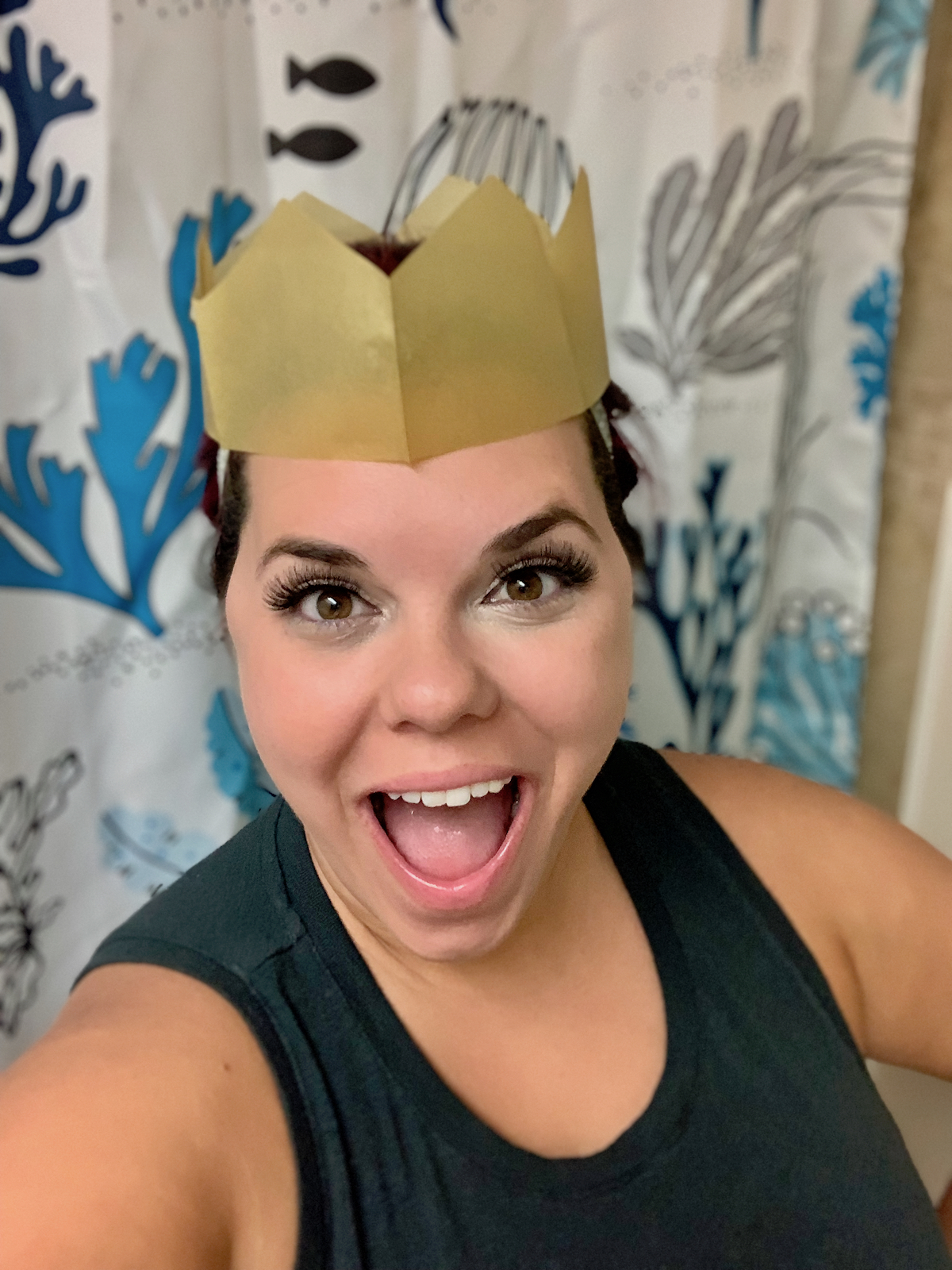 woman smiling with mouth open wearing gold paper crown on head