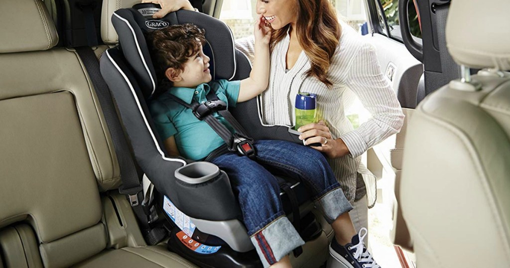 mom standing next to child in carseat in car