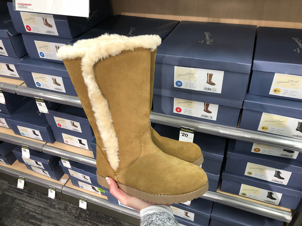 hand holding fur-lined boots in front of store display