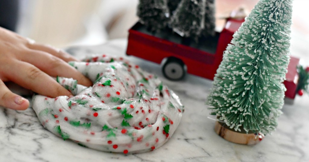 hand playing with Christmas slime by decorations