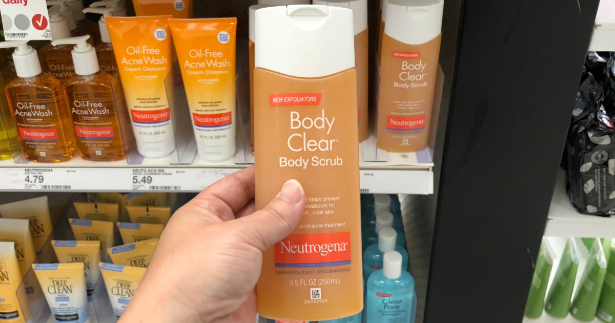 hand holding a bottle of neutrogena body scrub in front of a store display