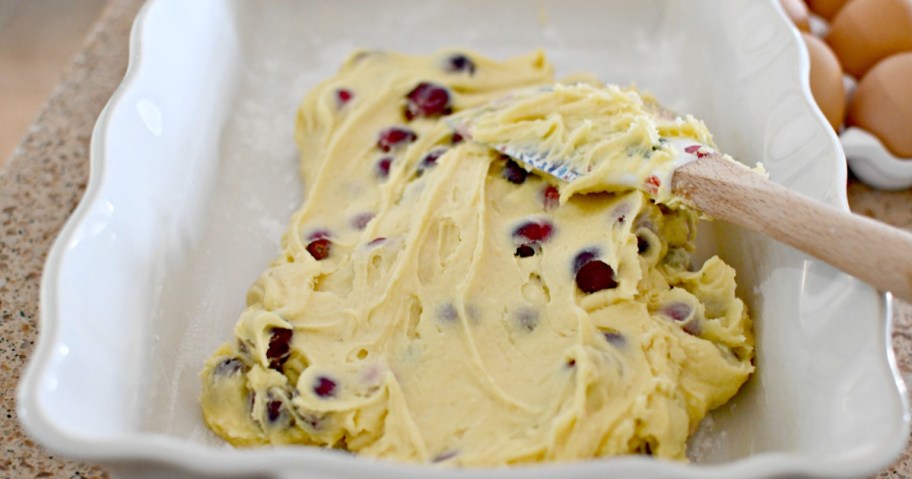 spreading cranberry Christmas cake in a baking dish