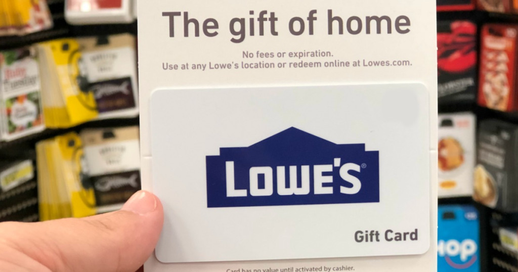 hand holding lowe's gift gard with gift cards in background