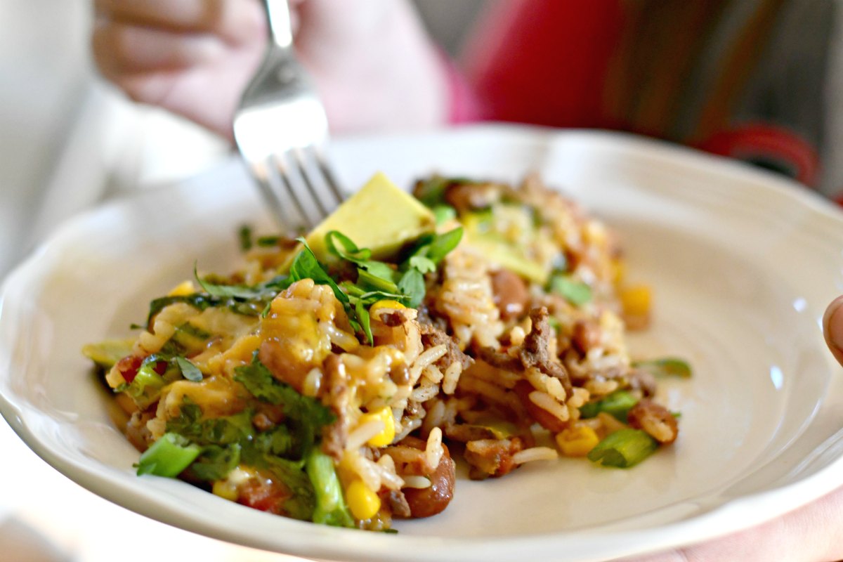 taco rice beans skillet casserole – a fork going into a plate of the casserole