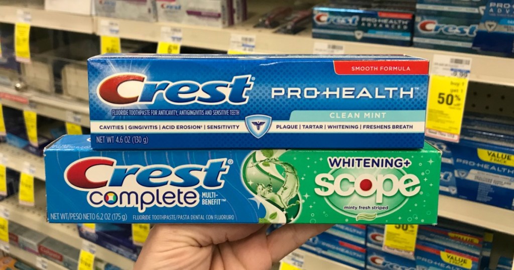 Hand holding Crest onlineplete and Pro-Health Toothpaste