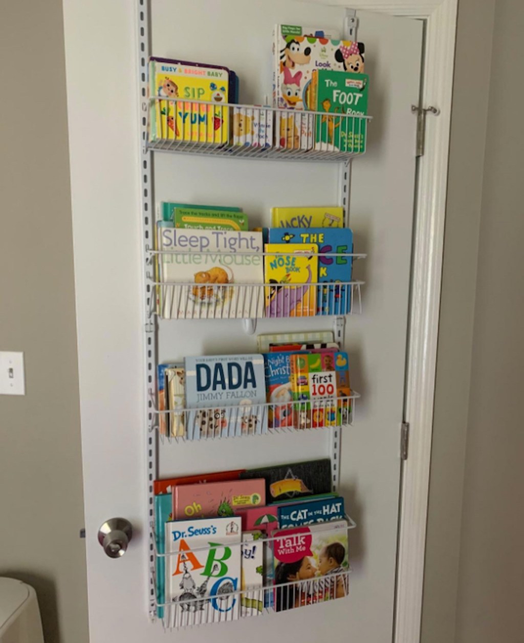 white wire bookshelves hanging on door filled with childrens books